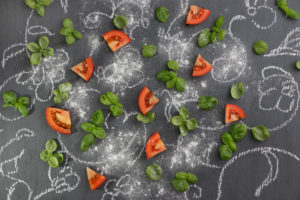 Tomatoes with basil on notice board painted with chalk Tomatoes with basil on notice board painted with chalk